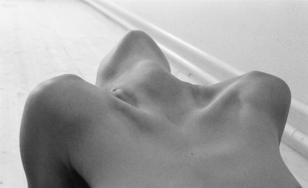 Black and white close-up of woman’s bare chest with head thrown back