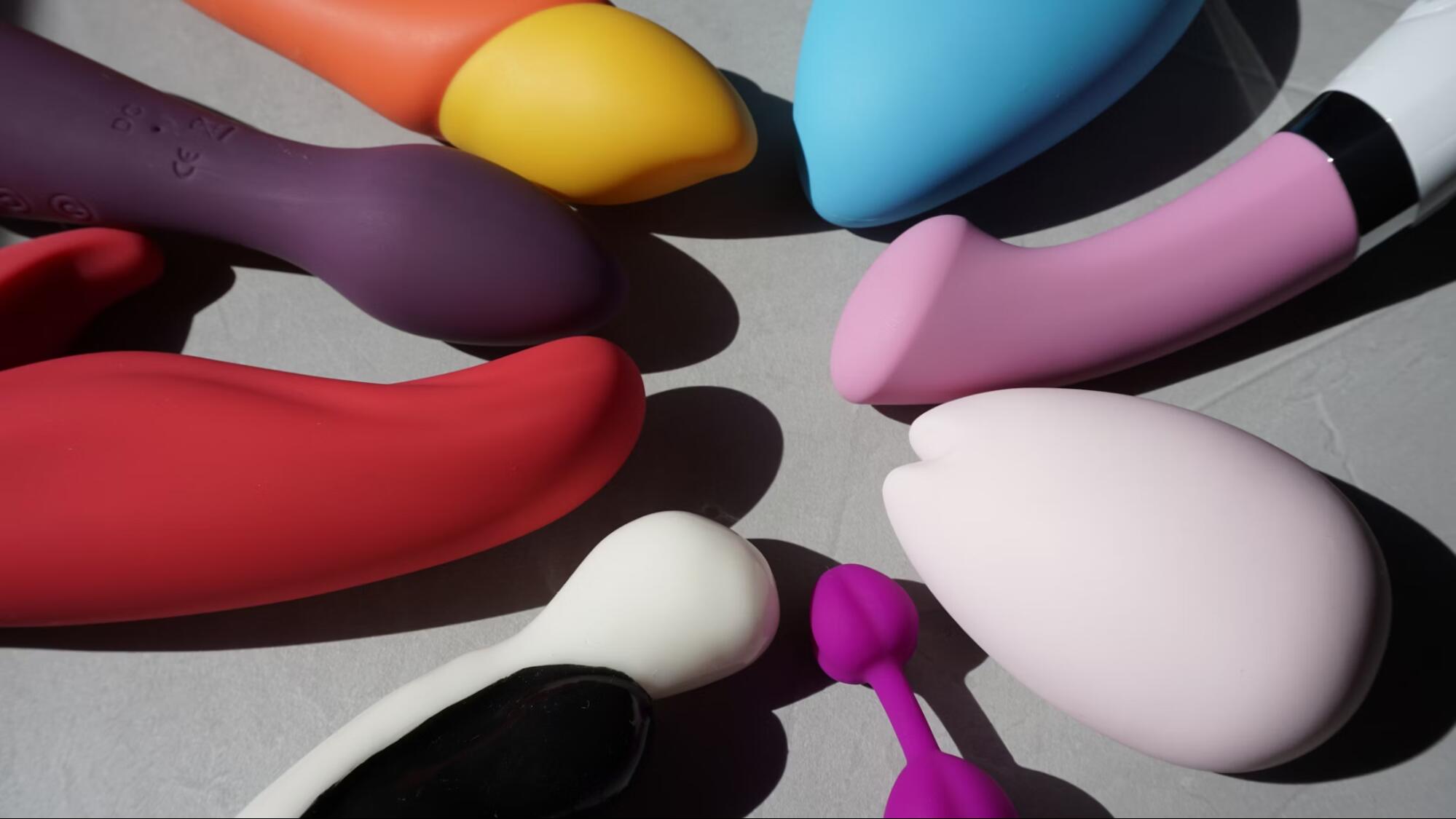Collection of colorful sex toys on a gray surface