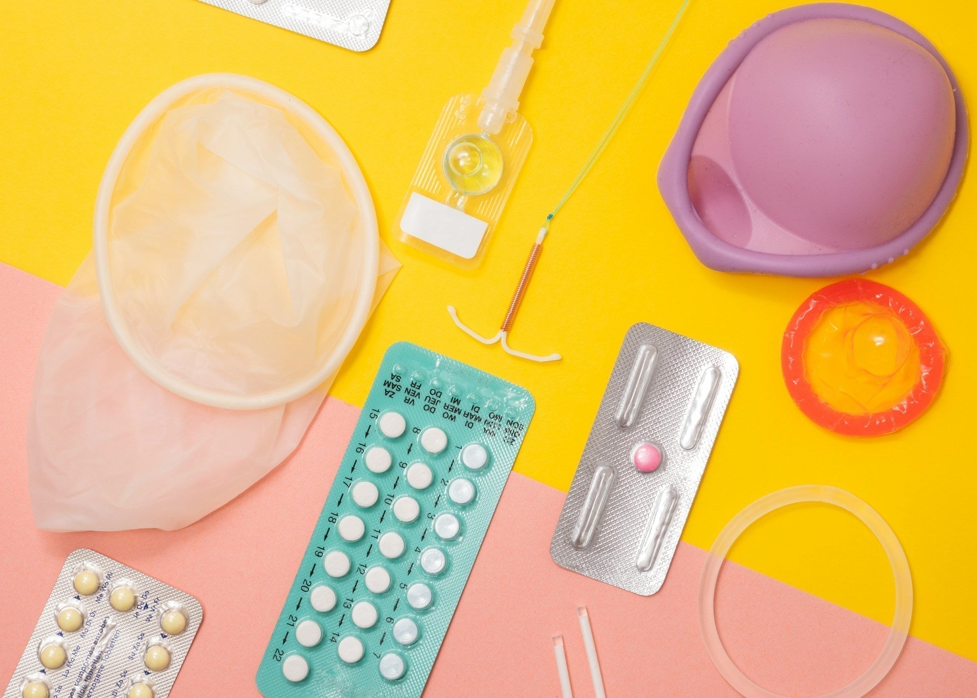 Collection of contraception supplies against a pink and yellow background