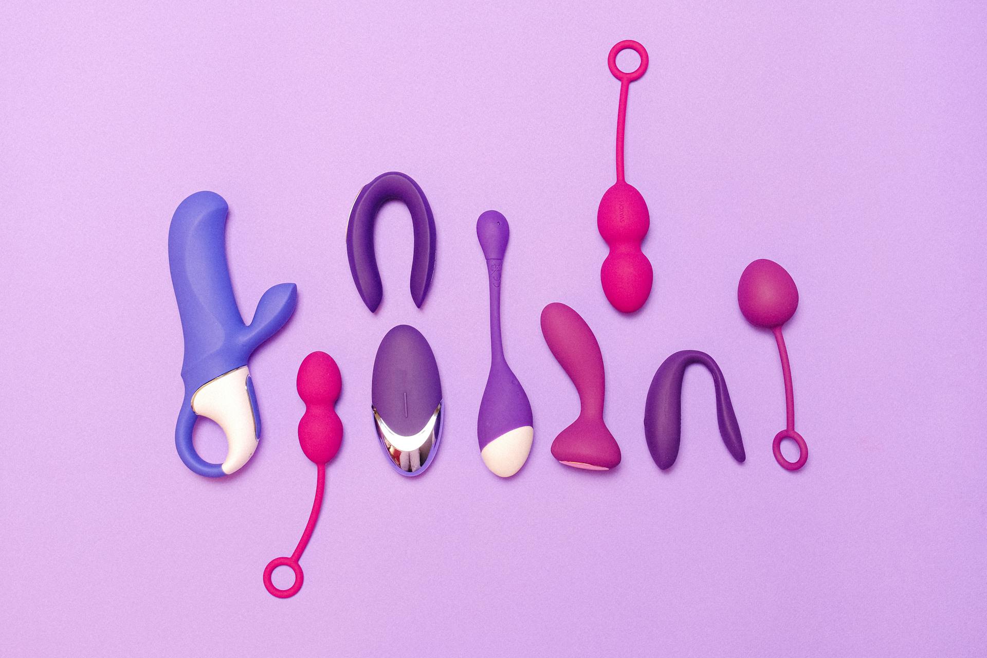 An assortment of sex toys on a purple surface